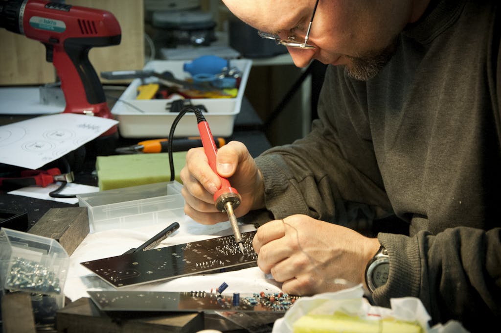A focused technician skillfully soldering a circuit board at a workbench, highlighting precision and craftsmanship.
